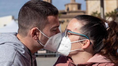 Una pareja se besa con mascarillas, en las que podra aplicarse el nanomaterial para eliminar el virus