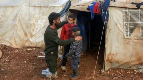 Ahmad Hamra y sus hijos fuera ante su tienda de campaña en un campamento sirio para desplazados, en el norte de Alepo