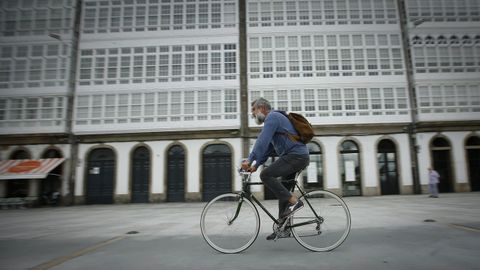 Un hombre pasea en bicicleta por la Marina, en A Coruña