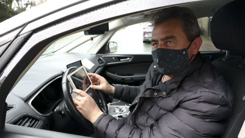 La falta de clientes condena a los taxistas compostelanos a eternas esperas en las paradas que muchos, como Manuel Pena (en la imagen), sobrellevan gracias a poder ver series en las tabletas o los móviles