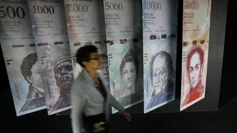 Una mujer pasa por un muestrario de los nuevos billetes de bolívares que se exhibe en la sede del Banco Central de Venezuela