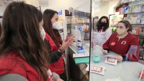 Laura y Natalia, de Cruz Roja, explican en una farmacia el programa y piden la colaboración de los farmacéuticos
