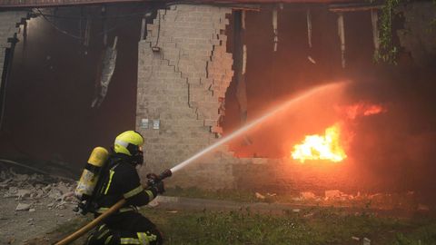 Un bombero se enfrenta a las llamas en una de las naves calcinadas