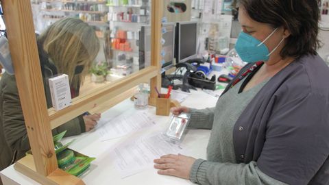 En la imagen, una madre firma el consentimiento informado en el momento de recoger el kit para la muestra en la farmacia de María Adrio