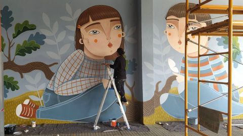 Abi Castillo creó dos grandes obras para el CEIP de Roxos con la ayuda de los alumnos de primaria. Los de infantil participaron también en el proceso con preguntas a la autora y dibujando en sus pizarrillas. La artista, más conocida por sus ilustraciones y trabajos en cerámica, lleva un par de años en el arte mural, un mundo que le divierte mucho, dice. Este es su primer trabajo en la comarca de Santiago, aunque ya había hecho antes otras obras a gran escala para centros educativos de la zona de Vigo