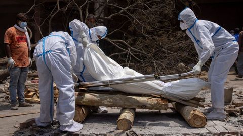 Un grupo de personas, preparando el cuerpo de una de las víctimas mortales del covid-19 para proceder a su cremación