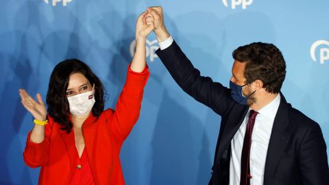 El líder del PP, Pablo Casado, alza el brazo de la candidata popular, Isabel Díaz Ayuso, tras confirmarse su victoria arrolladora en las elecciones de Madrid