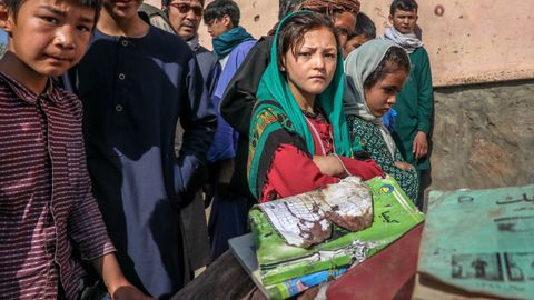 Un grupo de escolares vigilan los libros y cuadernos manchados de sangre de sus compañeros muertos en el atentado en la escuela de Kabul