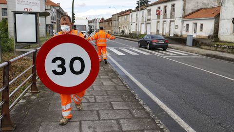 Operarios cambiando la señalización en Santiago este lunes