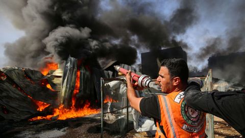Un bombero palestino intenta sofocr el incendio en una fábrica en la que impacto un misil israelí