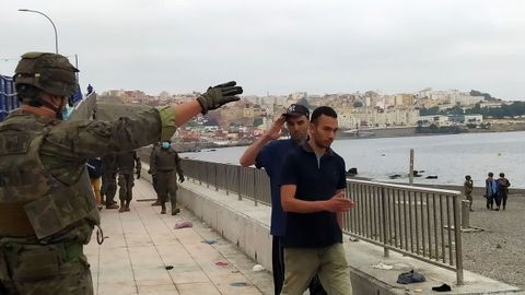 Un miembro del Ejército de Tierra da instrucciones a un grupo de inmigrantes