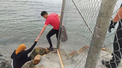 Dos inmigrantes escalan las rocas de uno de los espigones fronterizos de Ceuta