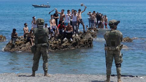 Marroquíes en las rocas del Tarajal, vigilados por soldados españoles