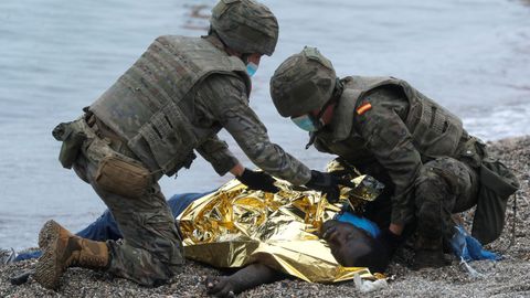 Soldados españoles auxilian a uno de los inmigrantes llegados a la playa del Tarajal