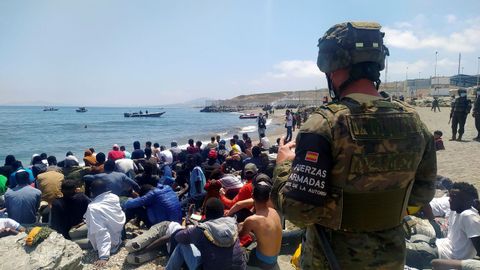 Un soldado vigila a un grupo de inmigrantes que lograron cruzar uno de los espigones fronterizos de Ceuta