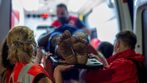 Efectivos de Cruz Roja atienden a un migrante con signos de hipotermia tras intentar cruzar a España por el agua en la playa de El Tarajal.