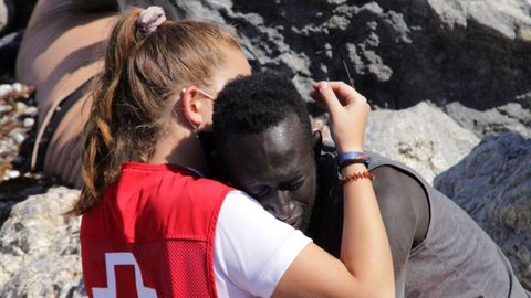 Una trabajadora de la Cruz Roja y un migrante que ha logrado cruzar uno de los espigones fronterizos de Ceuta este martes se abrazan