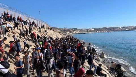 Un grupo de personas aguardan junto a la valla fronteriza que separa Fnideq, en Marruecos, y Ceuta