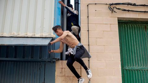 Dos menores migrantes escapando hoy de la nave ceutí del Tarajal donde eran atendidos