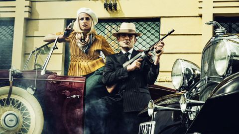 UN MIL RAYAS
Xoán Carlos Mejuto lleva un traje mil rayas de Félix Ramiro, corbata personalizada con iniciales, una tendencia que se estilaba en la época de Bonnie y Clyde, y un sombrero panamá. Iria Ares luce un top ocre de punto de abeja de Muy Castiñeiras, muy similar al que llevó Faye Dunaway en el filme de 1967. Además de un pañuelo, el complemento estrella de la temporada, anudado hacia atrás.