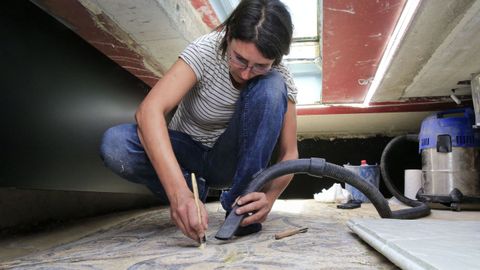 La restauradora Iria López limpia los restos de materiales que se sedimentan en los mosaicos romanos de Lugo