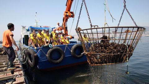 Un grupo de turistas a bordo de un barco mejillonero en la ría de Vigo.