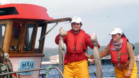 Dos turistas durante una jornada de pesca a bordo de un barco de pesca en O Grove.