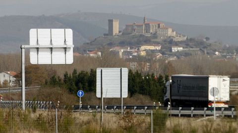 Tráfico por el tramo monfortino de la N-120, con la torre medieval de San Vicente al fondo