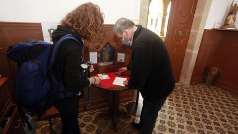 Andrés Garcìa le sella la credencial a una peregrina que empieza el Camino en Sarria