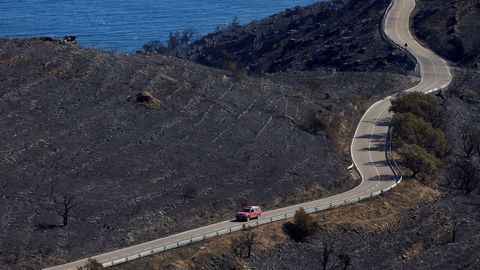 Un automóvil circula por la carretera que discurre por la zona del incendio que, desde este viernes afectó al parque natural de Cap de Creus y que fue estabilizado este domingo.