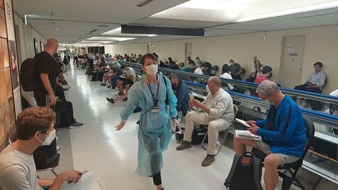 Una voluntaria, con una prenda de protección, trata de organizar la llegada de una de las delegaciones olímpicas a Narita