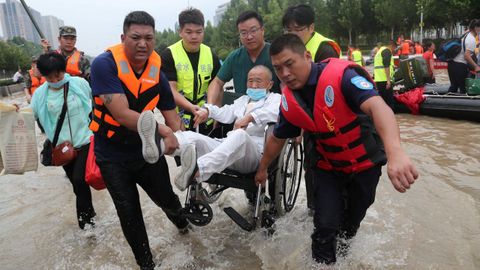 Equipos de rescate evacúan a una persona en silla de ruedas en la ciudad de Zhengzhou