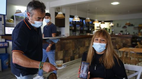María, de Vilagarcía pero con piso de veraneo en Sanxenxo, mostrándole a Fran, responsable de la cafetería Gran Suqui, el test de antígenos negativo para poder acceder al interior del local a tomarse un café