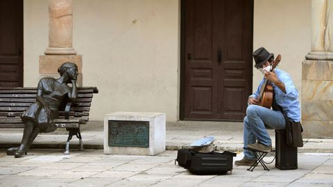 Un guitarrista callejero ameniza a los turistas en la plaza de la catedral de Oviedo