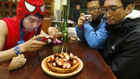 Peregrinos ante un plato de pulpo á feira en Melide.