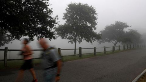 Dos turistas caminan entre la niebla en el Monte Naranco de Oviedo