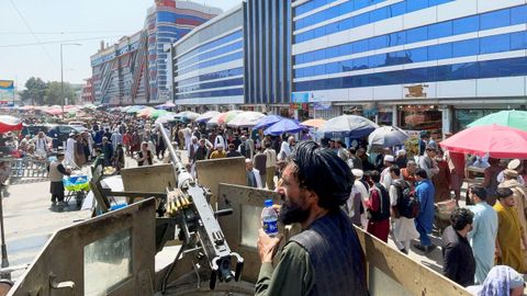 Un talibn fuertemente armado vigila a la multitud ante un mercado de cambio de divisas en Kabul.