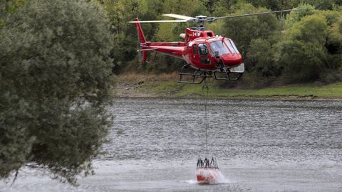 Un helicóptero carga en el río Sil para llevar agua al incendio de Ribas de Sil.