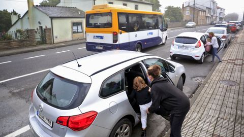 Los pequeños de Baamonde suben al coche mientras el autobús escolar pasa de largo.