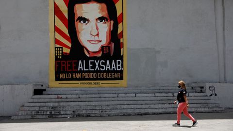 Una mujer paseando en Caracas ante un cartel que pide la libertad de lex Saab.