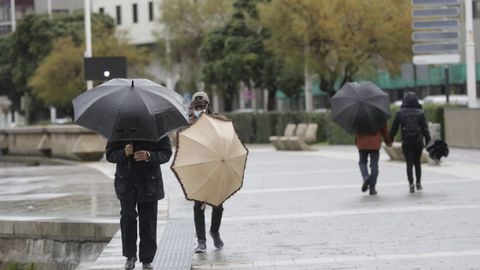 Gente sosteniendo los paraguas esta mañana en A Coruña