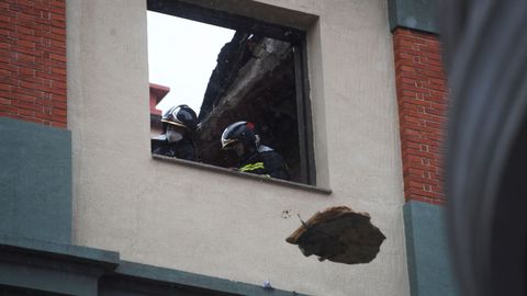Unos bomberos lanzan escombros por una ventana prxima a la azotea del colegio San Vicente Pal en Gijn
