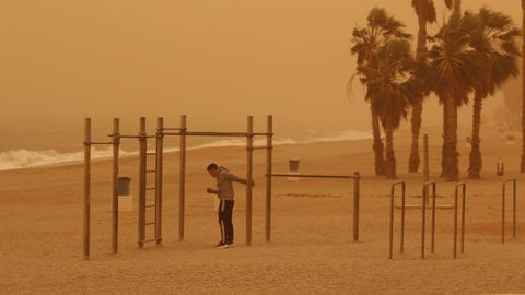 Un joven hace deporte en la playa de Aguadulce, Roquetas de Mar ( Almería) bajo la intensa calima