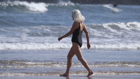 Una mujer se mete en el mar en la playa de San Lorenzo de Gijón