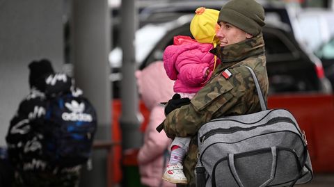 Un soldado polaco ayuda a un niño refugiado de Ucrania. 