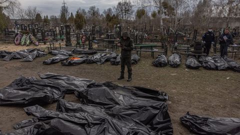 Un policía colabora con el personal forense en la identificación de cadáveres en Bucha