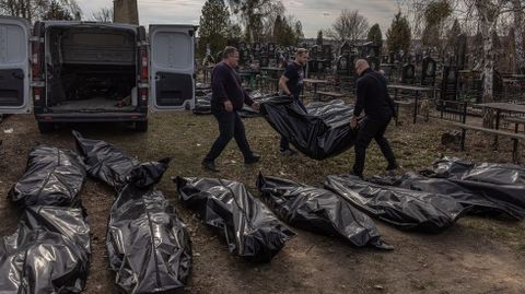 Voluntarios de Bucha y trabajadores de las funerarias entierran en sacos de plstico a las decenas de civiles muertos en este suburbio de Kiev. 