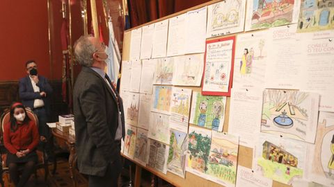 El alcalde de Santiago observa los trabajos ganadores en la edición del 2021 de «Coñece o teu concello», en el acto de entrega de premios en el Pazo de Raxoi