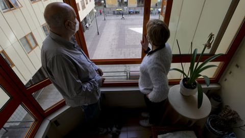 Luis y su mujer, María José, en la ventana de su salón que da a la plaza de la calle Socorro