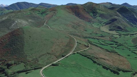 En primer plano, el pico Mirayu (Grado, Asturias), visto desde la cara sur. La carretera que lo bordea es el Camino de la Mesa. A la derecha, la vega húmeda donde habría perecido un gran contingente de caballería musulmana